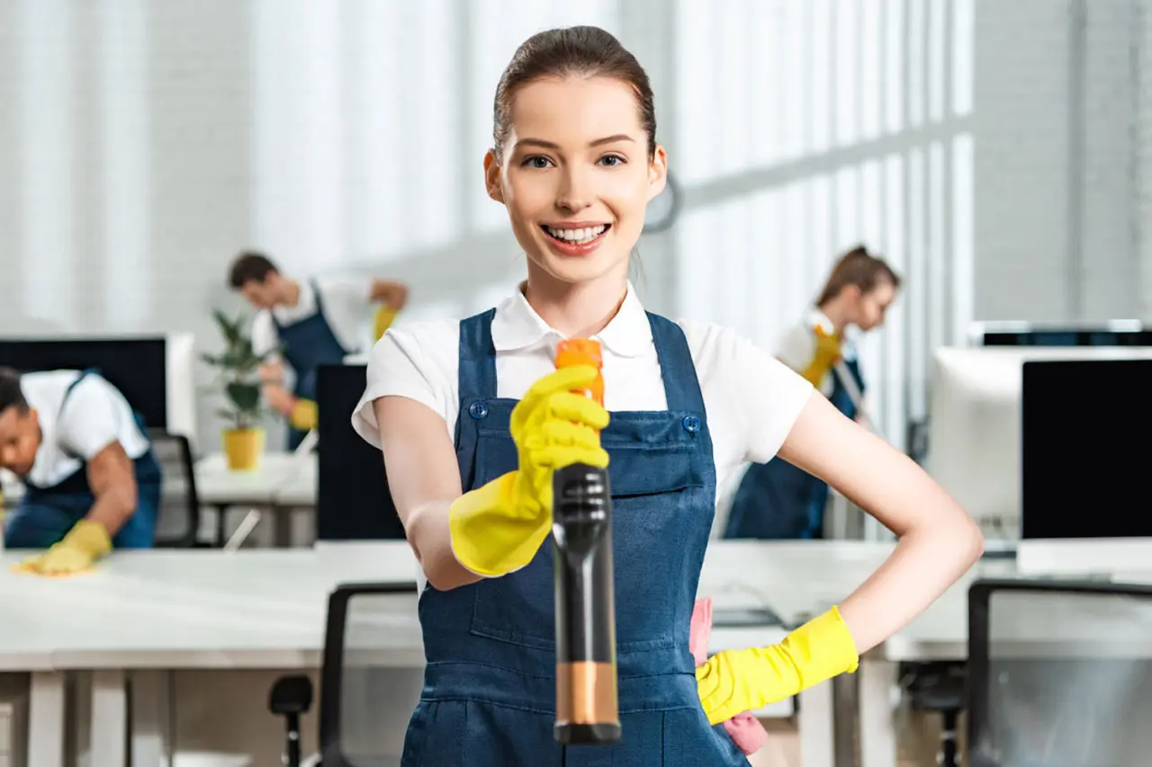 cheerful cleaner in overalls standing with hand on GJR6Y8A.jpg